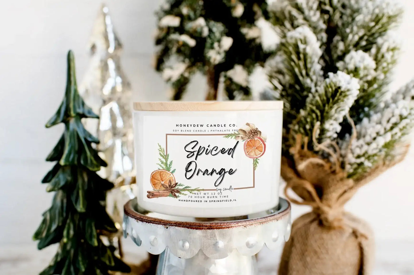 Spiced Orange candle from Homebody Candle Co. with decorative Christmas trees in the background.