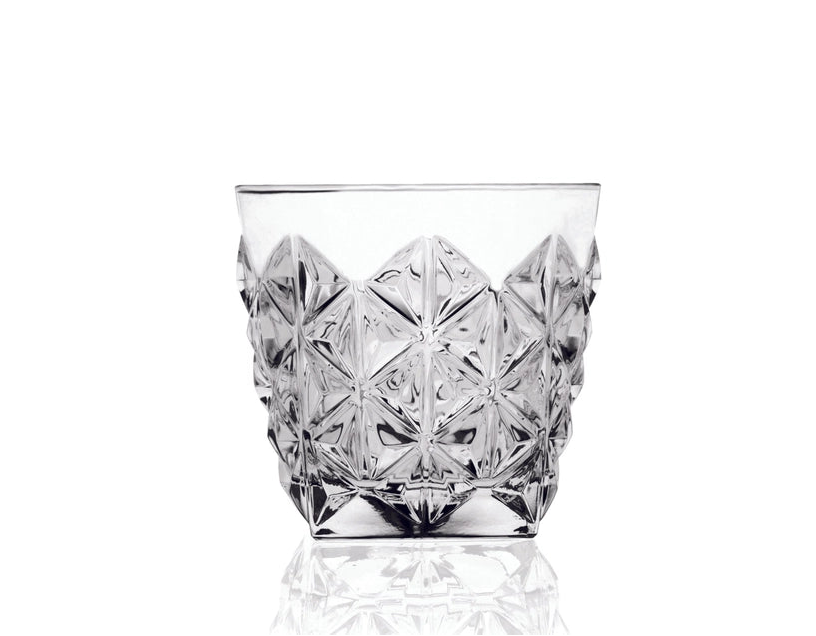 Clear glass tumbler with diamond cut pattern on a white background