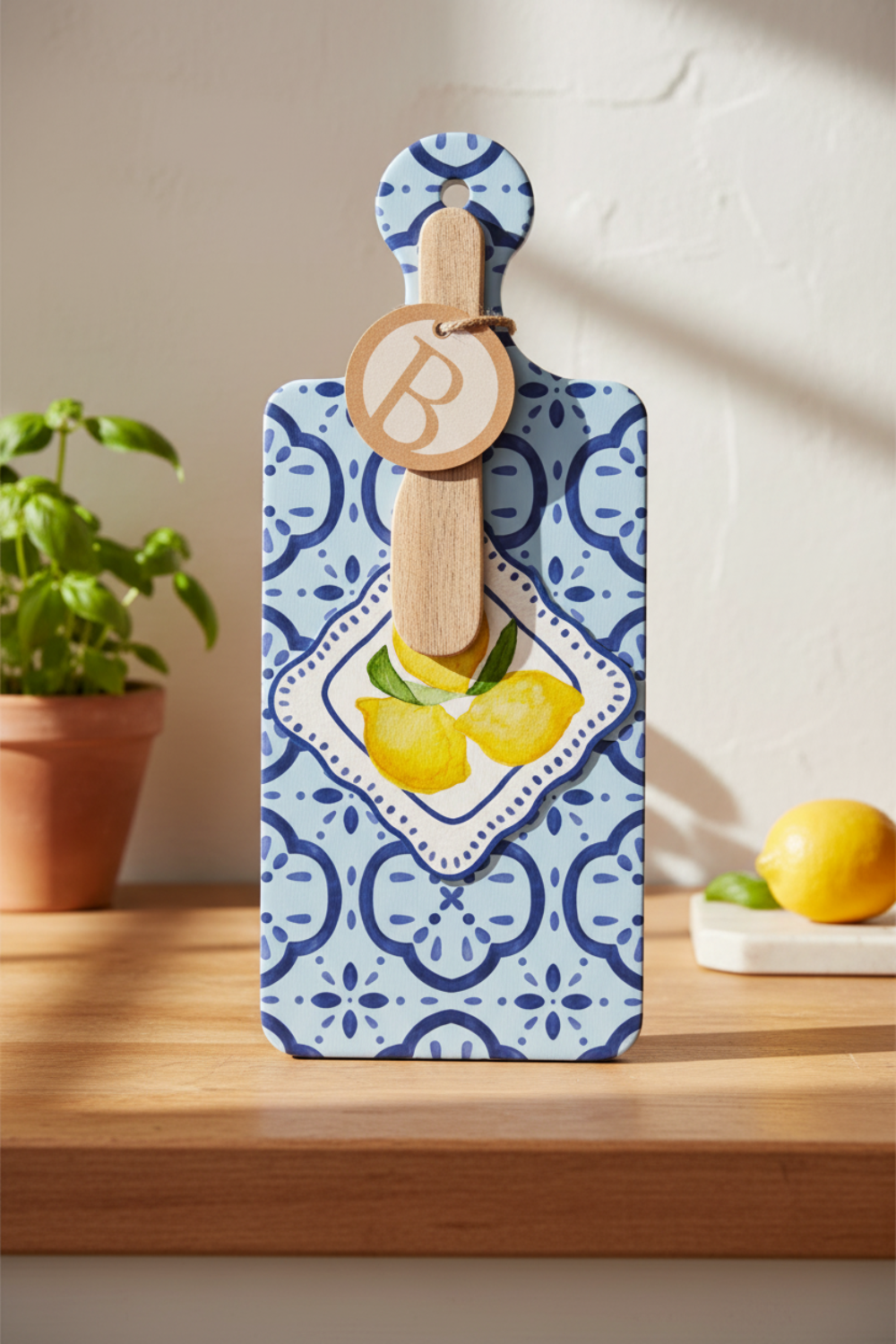 Decorative cutting board with lemon design and wooden handle on a blue patterned card.