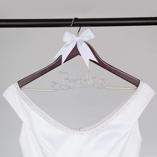 White bridal top on a 'Bride' hanger with a white bow against a gray background