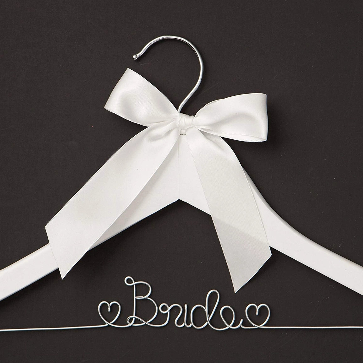 White hanger with a large white bow on a black background