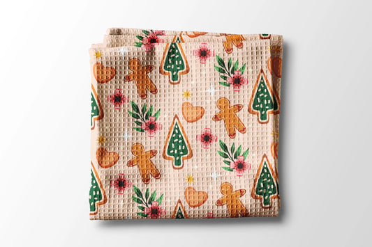 Waffle-textured blanket with Christmas-themed cookies and trees on a light background