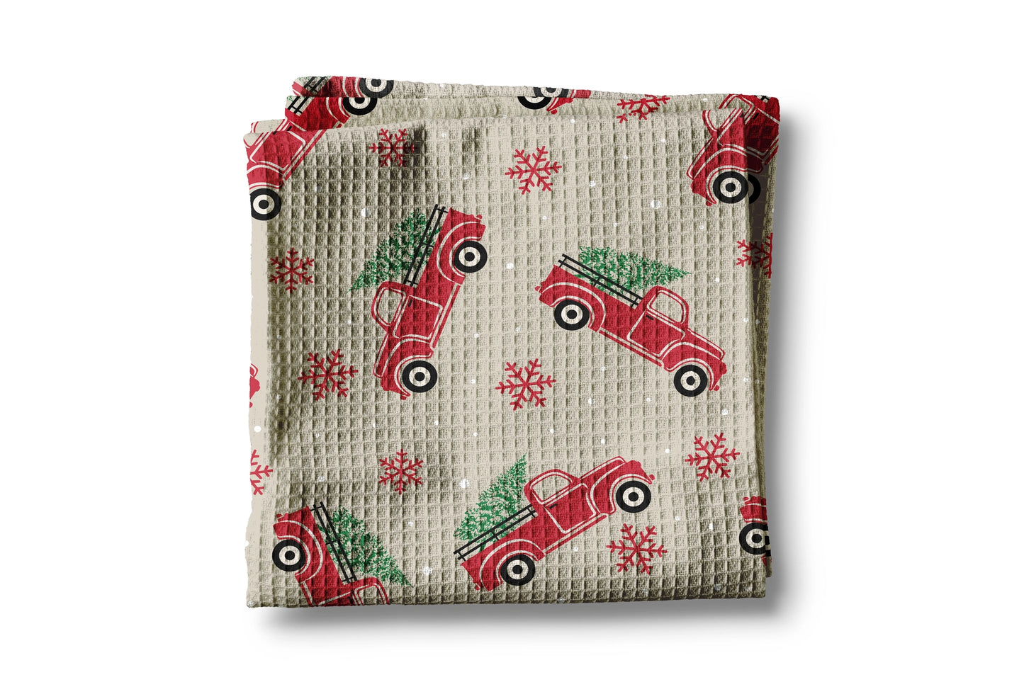 Folded fabric with red truck and Christmas tree pattern on a beige background