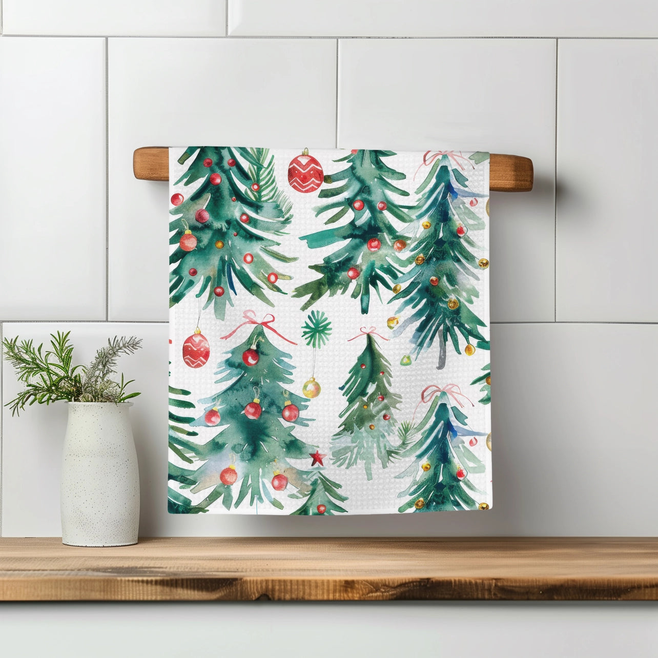 Decorative towel with Christmas tree pattern on a wooden towel rack against a tiled wall.
