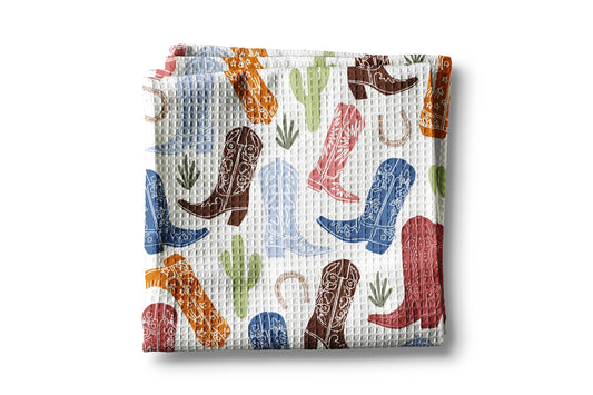 Waffle-textured blanket with colorful cowboy boot and cactus pattern on a white background