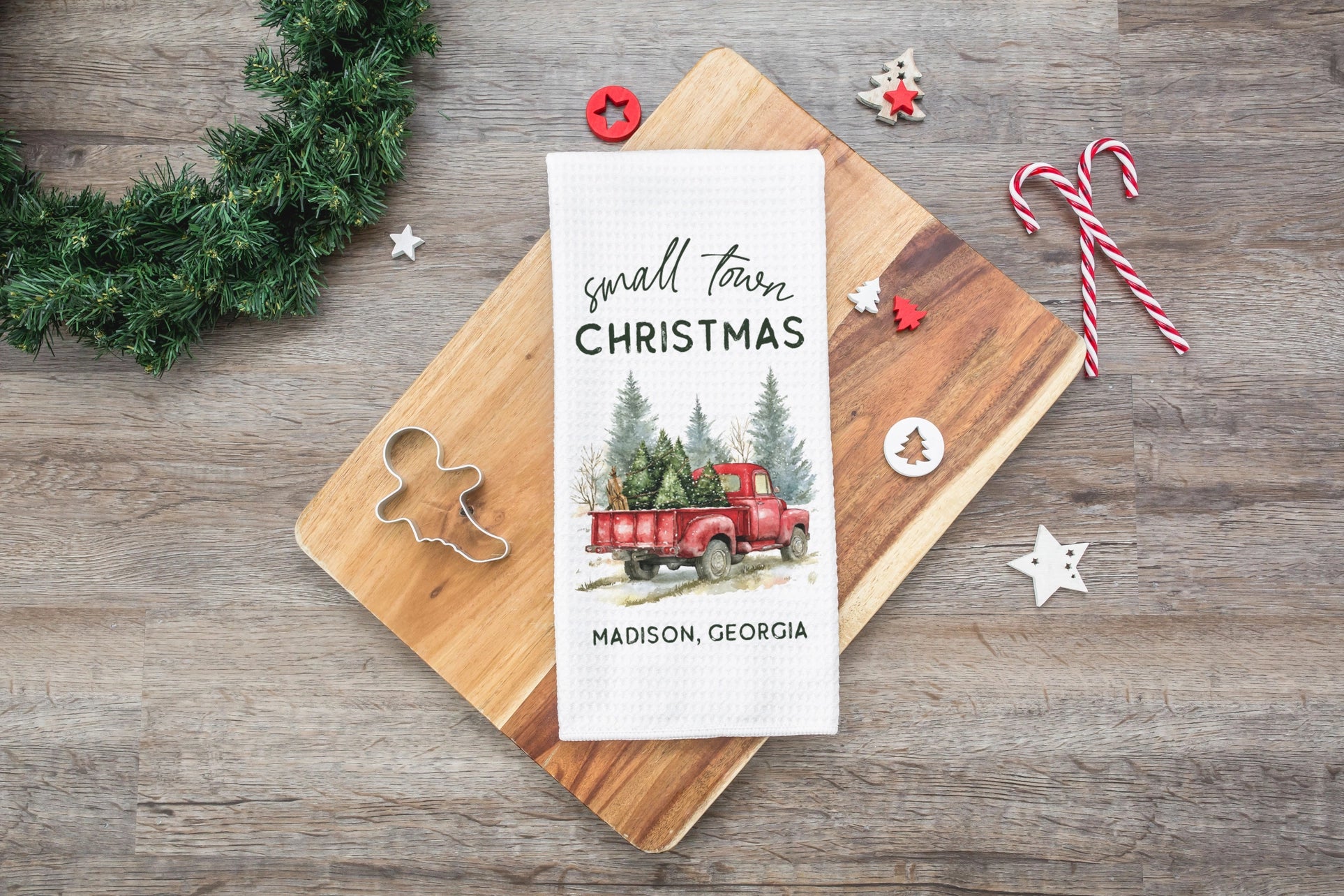 Christmas-themed card with red truck and Christmas trees on a wooden board with festive decorations.