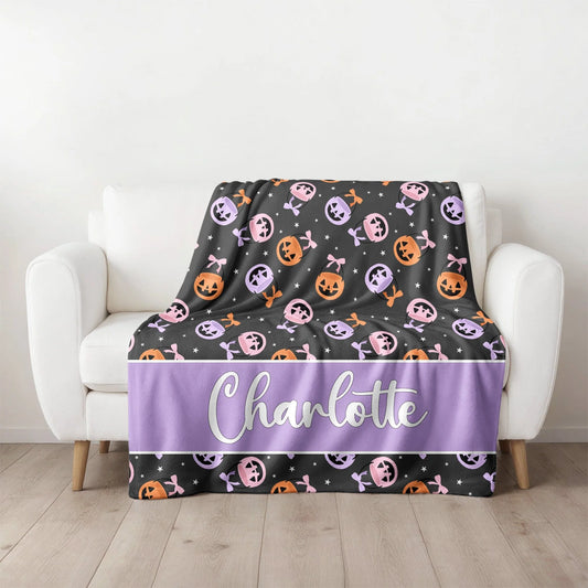 Halloween-themed blanket with pumpkins and bones on a white couch.