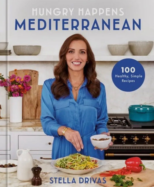 Cookbook cover featuring a woman in a kitchen with the title 'Hungry Happens Mediterranean' by Stella Drivas.