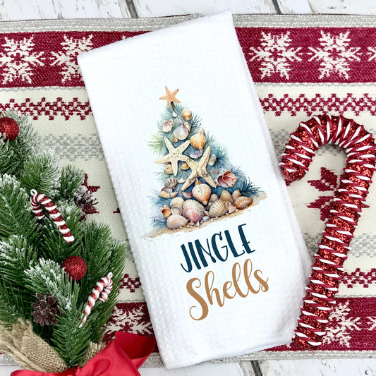 Towel with Christmas tree design and 'Jingle Shells' text on a decorative mat.