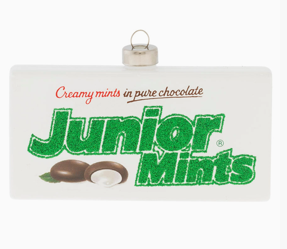 A white rectangular candy-themed ornament featuring the Junior Mints logo in green, with red text reading 'Creamy mints in pure chocolate' and a small chocolate-and-mint illustration near the bottom. A silver hanging loop is attached at the top.