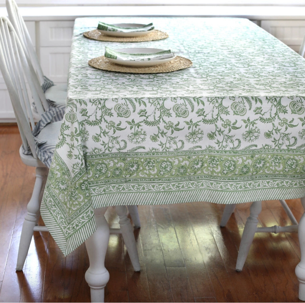 Dining table with a green and white patterned tablecloth on a wooden floor.
