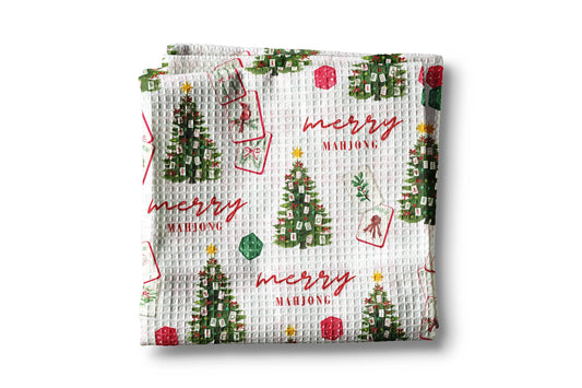Waffle-textured towel with Christmas tree and 'merry mahjong' pattern on a white background