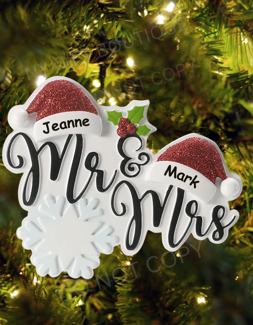 Personalized 'Mr & Mrs' ornament with red hats on a Christmas tree.