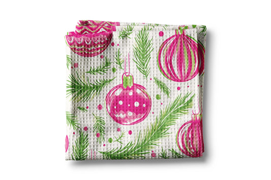 Waffle-textured towel with pink Christmas ball and green pine tree pattern on a white background