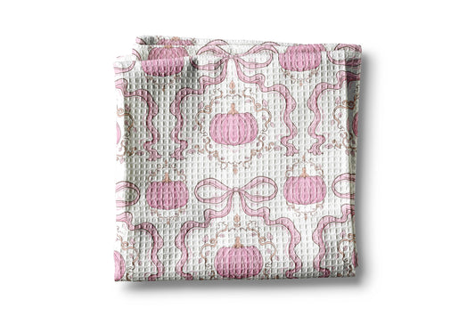 Folded fabric with pink pumpkins and ribbons pattern on a white background
