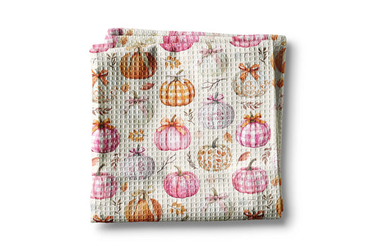 Waffle-textured blanket with pumpkins and leaves pattern on a white background