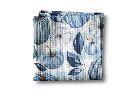 Folded fabric with blue pumpkin and leaf pattern on a white background