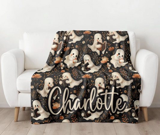 Halloween-themed blanket with ghosts and the name 'Charlotte' on a white armchair.