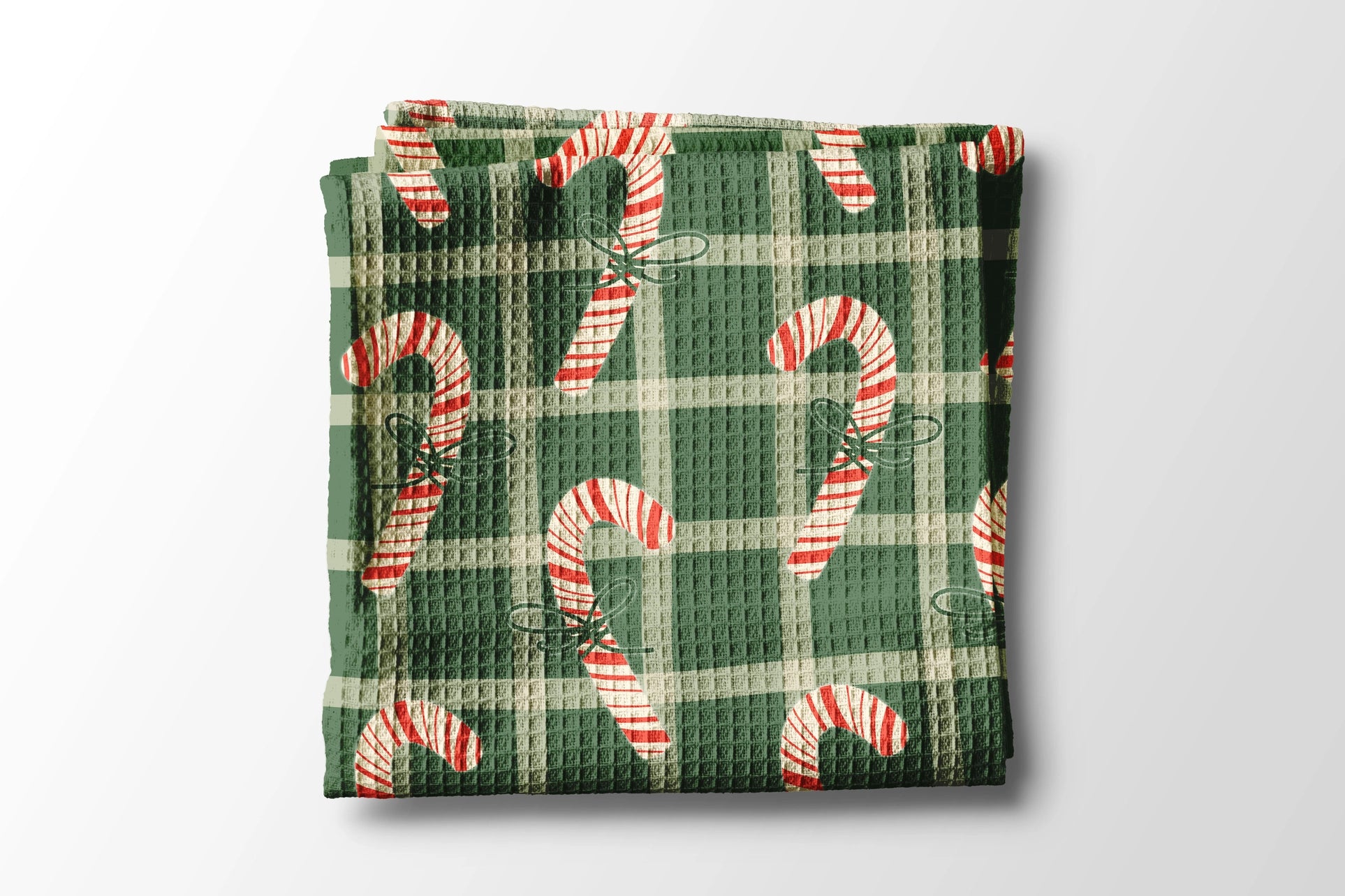 Folded green waffle towel with candy cane pattern on a light gray background