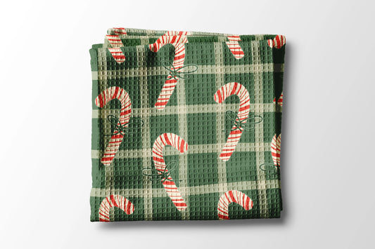 Folded green waffle towel with candy cane pattern on a light gray background