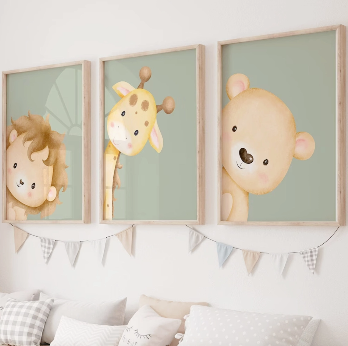 Set of three sage green nursery wall art prints featuring a watercolor lion, giraffe and bear peeking into the frames, displayed in natural wood frames above a neutral nursery bed.