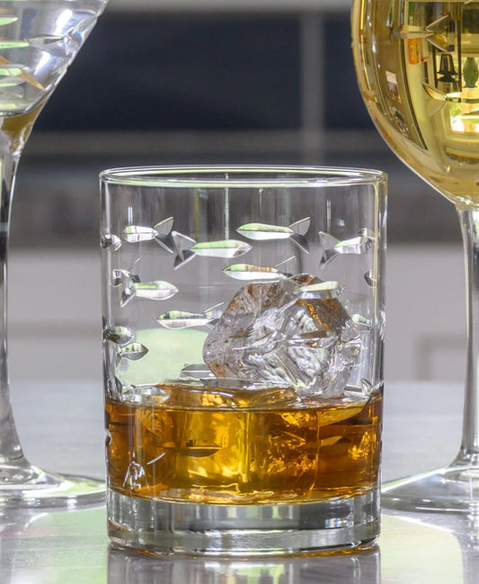 Set of etched glassware including a martini glass, wine glass, and rocks glass on a reflective surface.