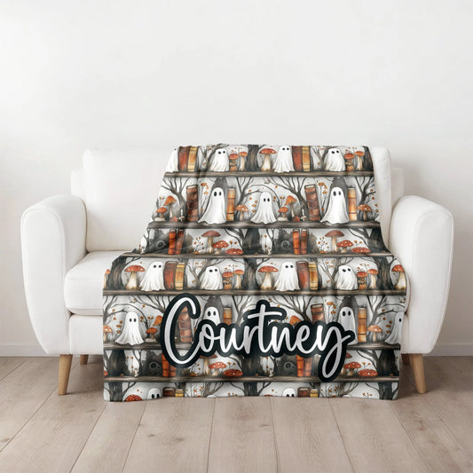Halloween-themed blanket with ghosts and pumpkins on a white armchair.