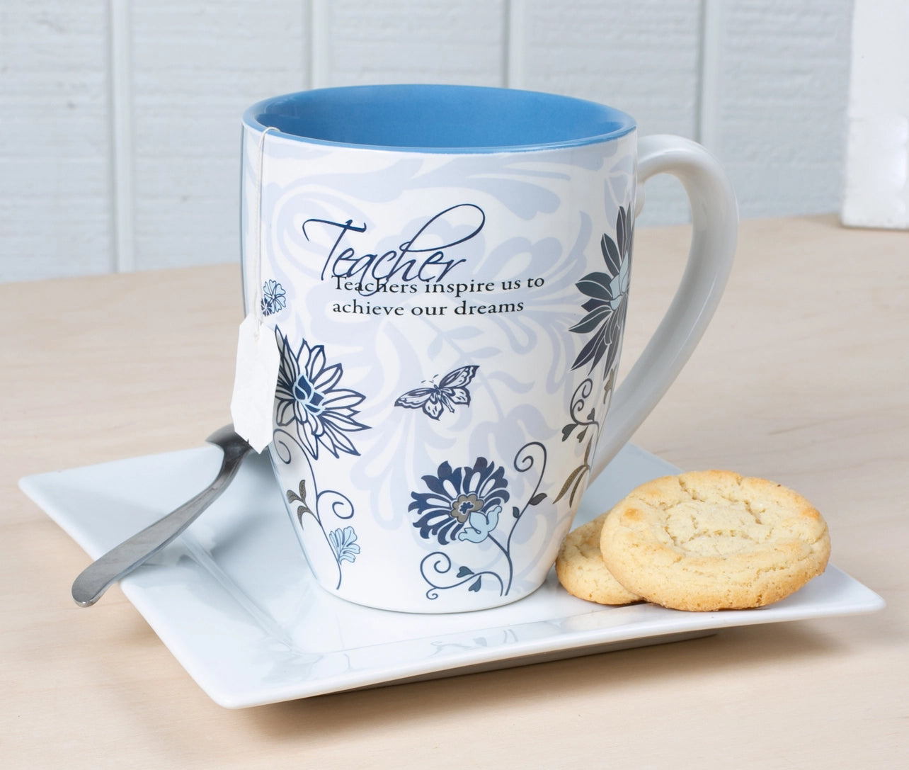 Mug with floral design and text on a plate with cookies and a spoon
