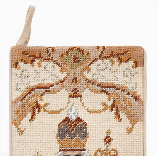 Close-up of ivory nutcracker needlepoint Christmas stocking with decorative bows, ribbon details and metallic gold accents