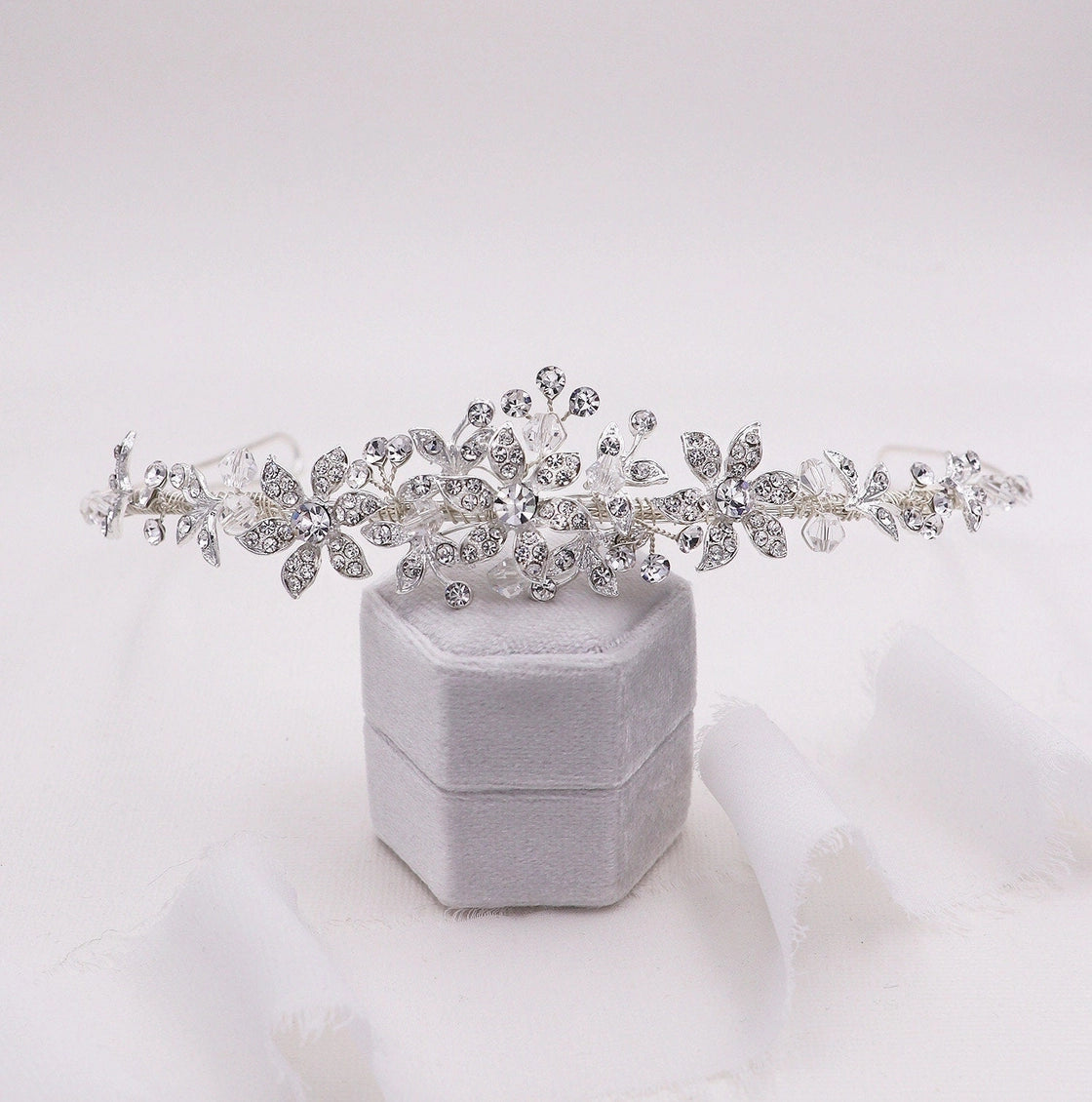 Silver tiara on a gray velvet box against a white background