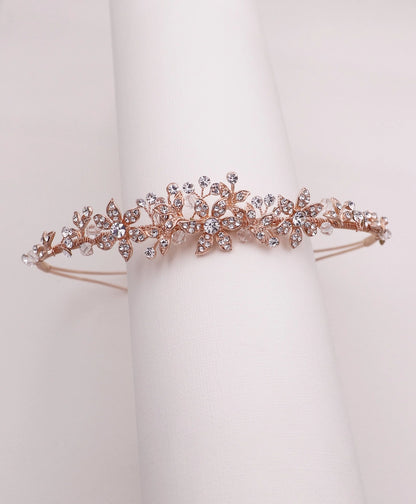 Rose gold tiara with crystal embellishments on a white stand
