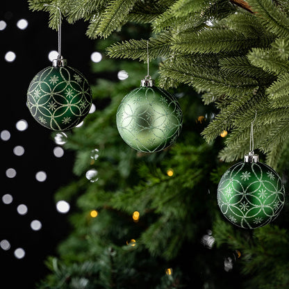 Green Christmas ornaments with silver patterns on a decorated tree.