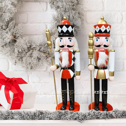 Two nutcrackers in festive attire with a white brick wall and gift box in the background.