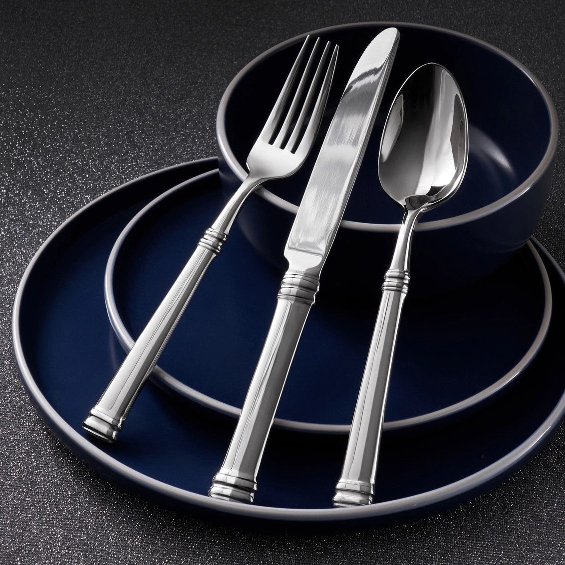 Silver cutlery set on dark blue plates with a dark background