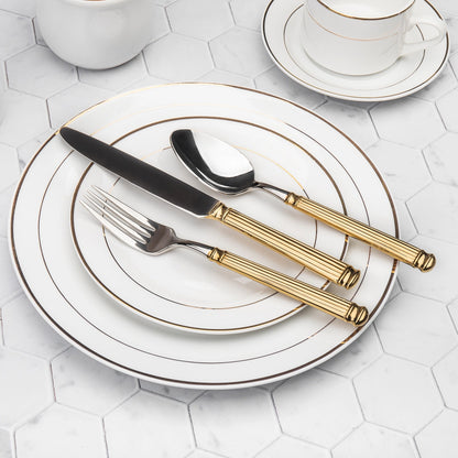 Set of gold and black cutlery on a white plate with a geometric patterned background
