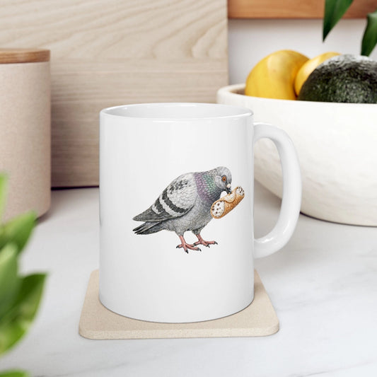 White mug with a pigeon design on a coaster, placed on a surface with a plant and container in the background.