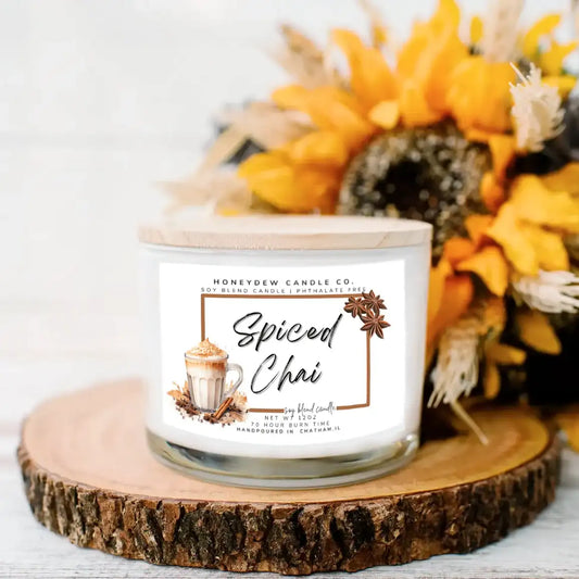Spiced Chai candle on a wooden coaster with a floral arrangement in the background