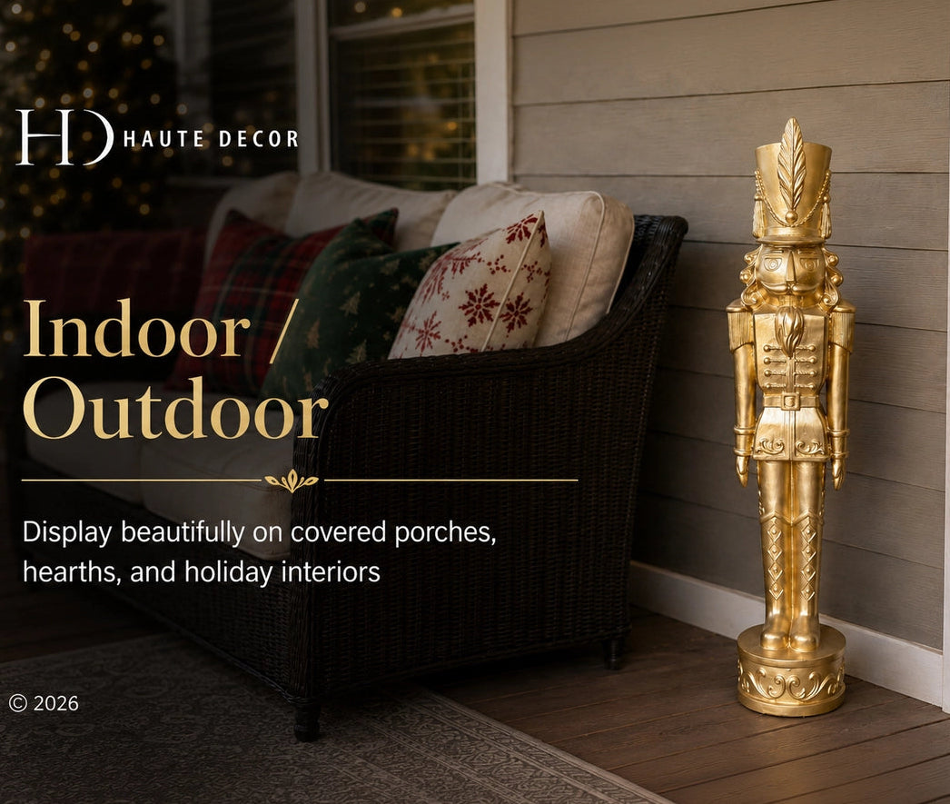 A tall decorative gold nutcracker stands on a wooden porch beside a dark wicker outdoor chair with patterned pillows. Text on the left reads 'HD HAUTE DECOR' and 'Indoor / Outdoor', with additional copy about displaying decor on covered porches and hearths.