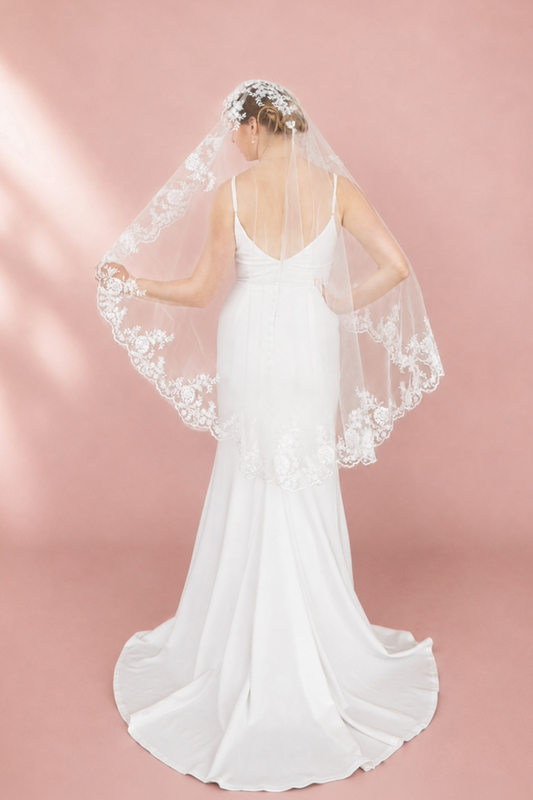 Bride wearing 48-inch ivory fingertip wedding veil with delicate scalloped floral lace edge