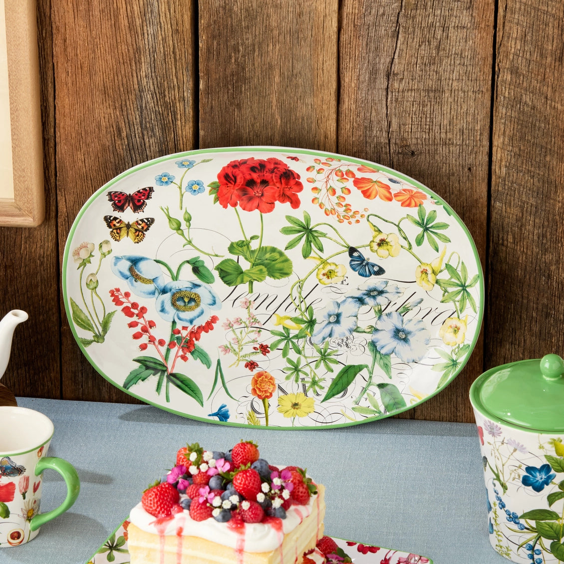 Decorative floral plate with matching mugs on a wooden background