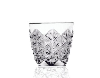 Clear glass tumbler with diamond cut pattern on a white background