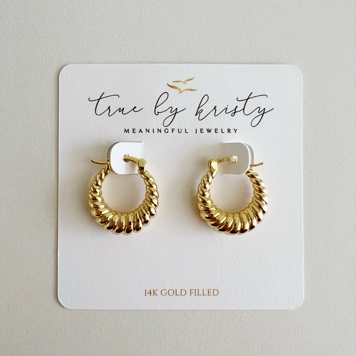 Gold hoop earrings on a 'true by kristy' branded card.
