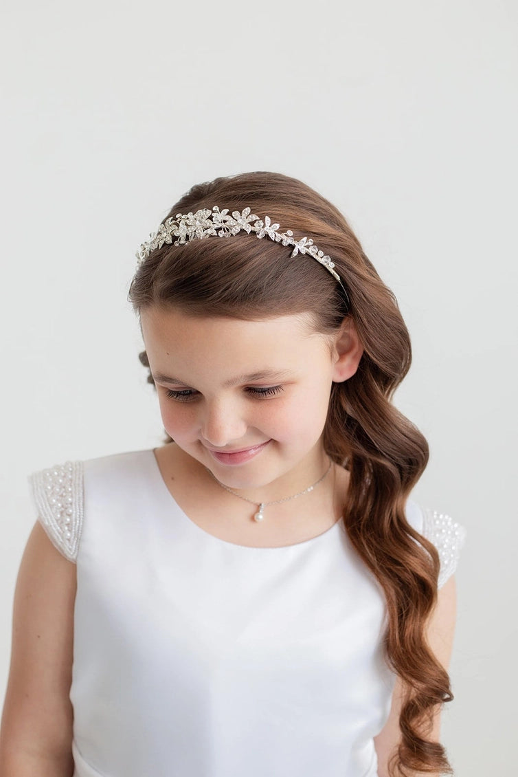 Young girl with a decorative headband and white dress on a light background
