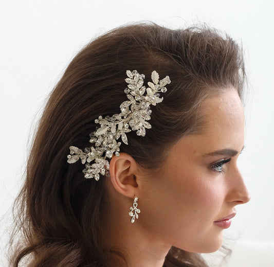 Woman wearing a decorative hairpiece and earrings with a white background