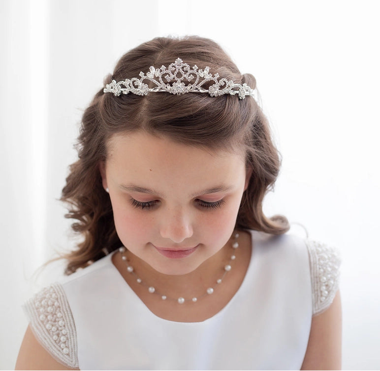 Young girl wearing a tiara and pearl necklace on a white background