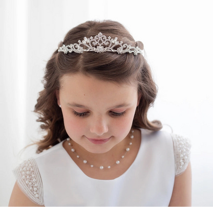 Young girl wearing a tiara and pearl necklace on a white background