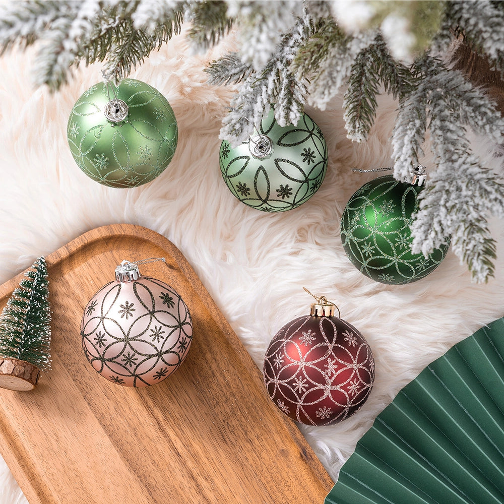 Decorative Christmas ornaments on a wooden tray with a white fur surface and tree branches.