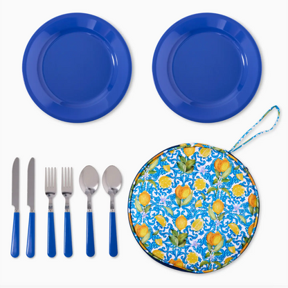 Blue plates, silverware, and a floral-patterned mat on a white background
