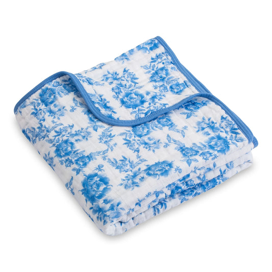 Folded blue and white floral blanket on a white background