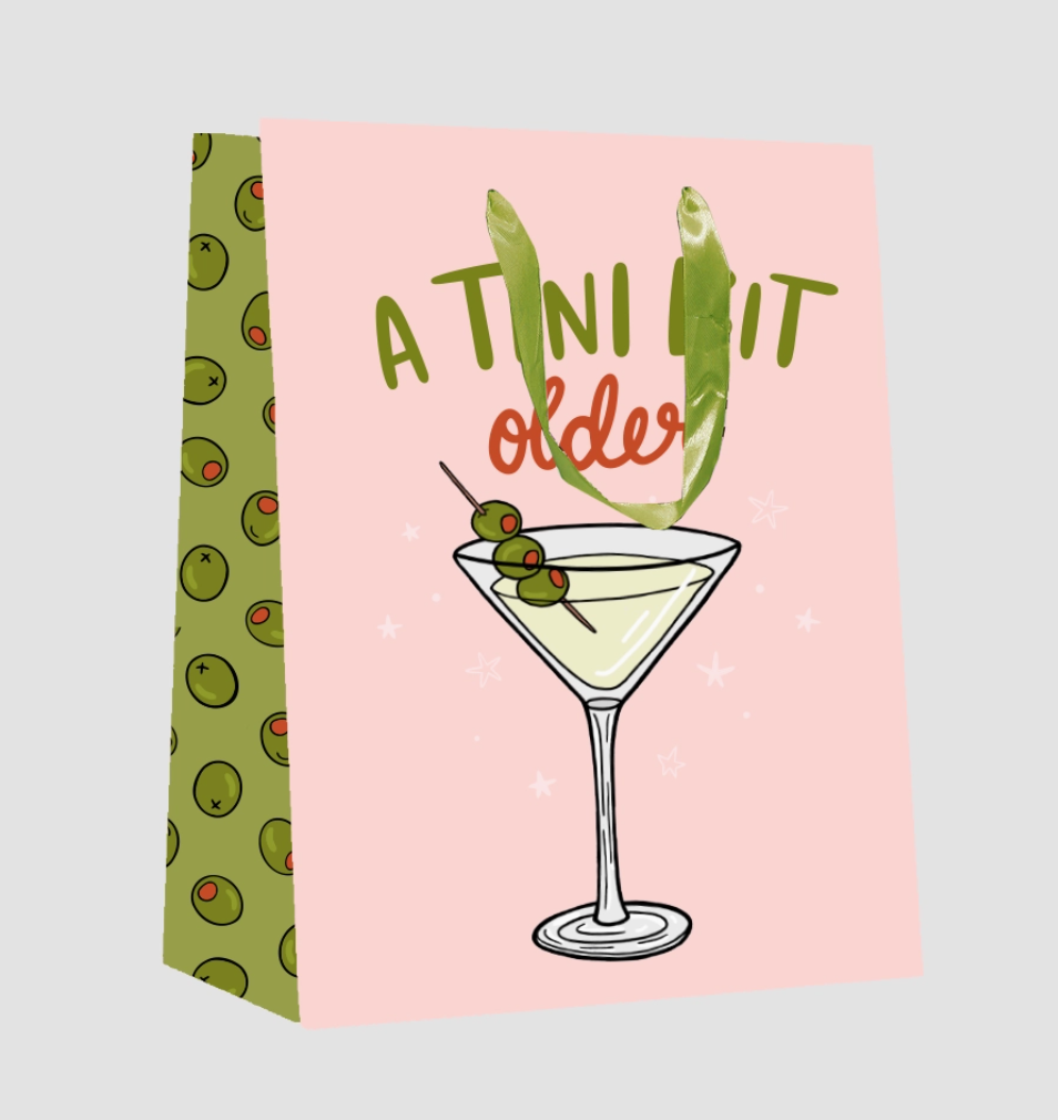 Two cocktail-themed towels, one with a martini glass and olives, the other with a humorous text design on a pink background.